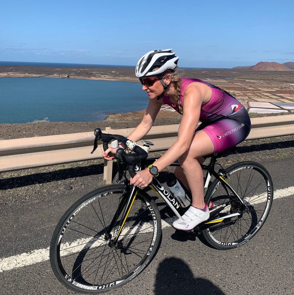 athlete cycling on a road with the sea in the background